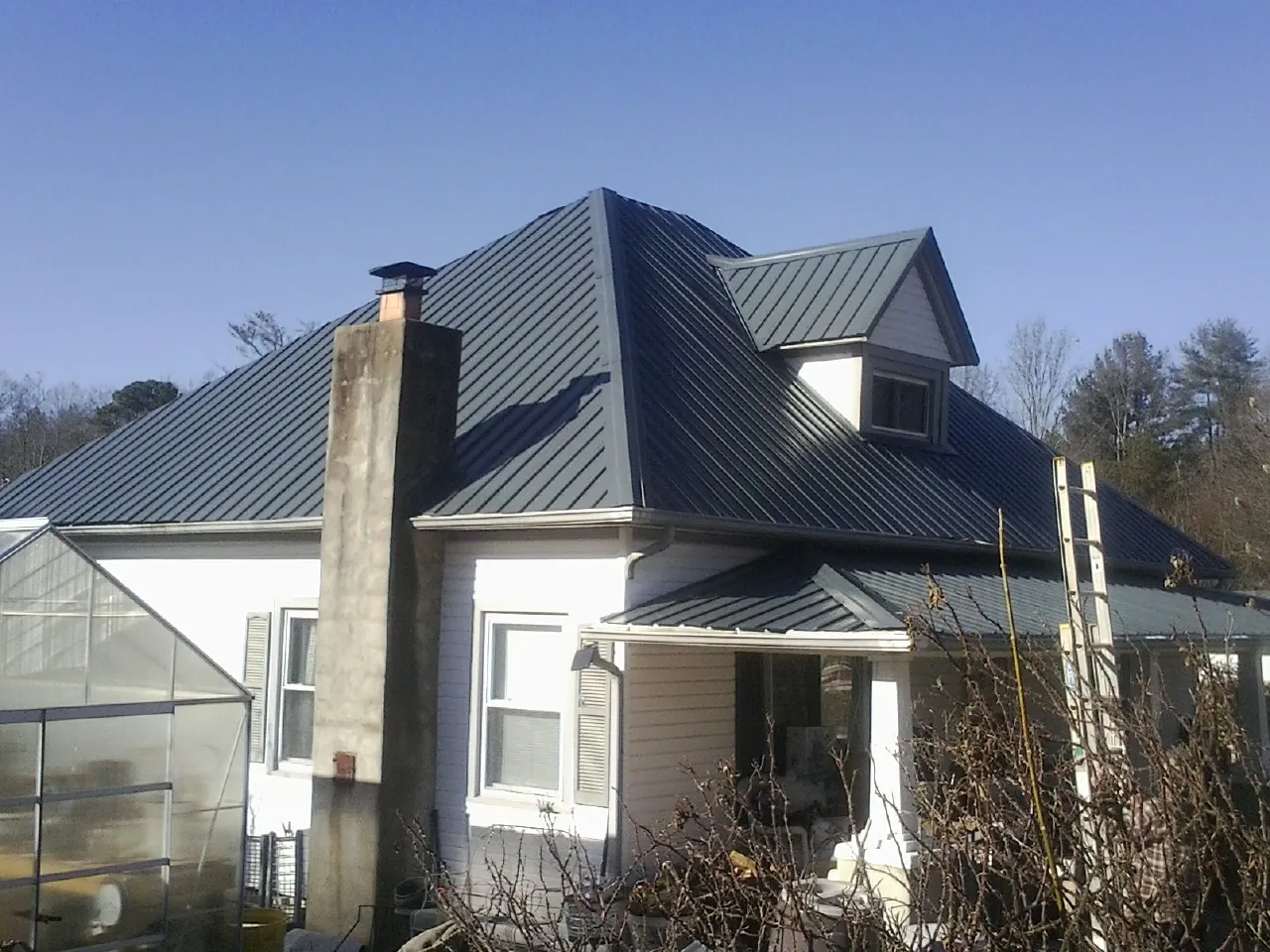 Dark blue standing seam metal roof on a white farmhouse with dormer — Slate & Tile Roof Repair by Roofing Brothers in Cardington