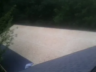 New OSB roof sheathing installed beside an existing shingle roof in Cardington