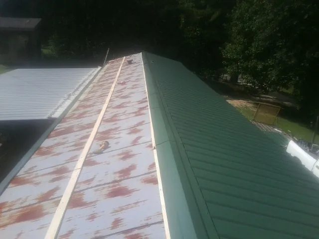 Old rusted panels beside newly installed green metal roofing — Wind Damage Roof Repair by Roofing Brothers in Cardington