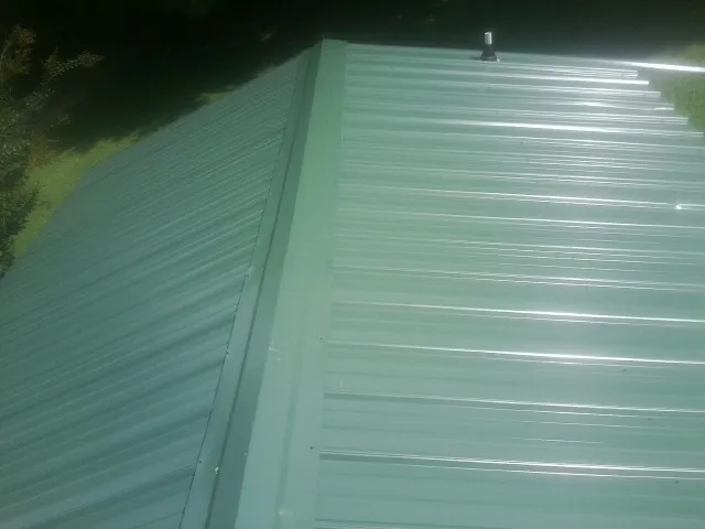 New green metal panels meeting at the ridge of a roof — Flat Roof Repair work by our crew in Cardington