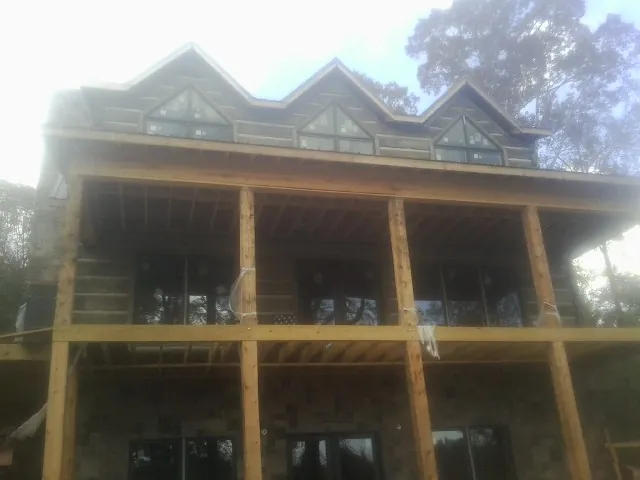 Dormers and porch framing on a large log home under construction — Roof Coating work by our crew in Cardington