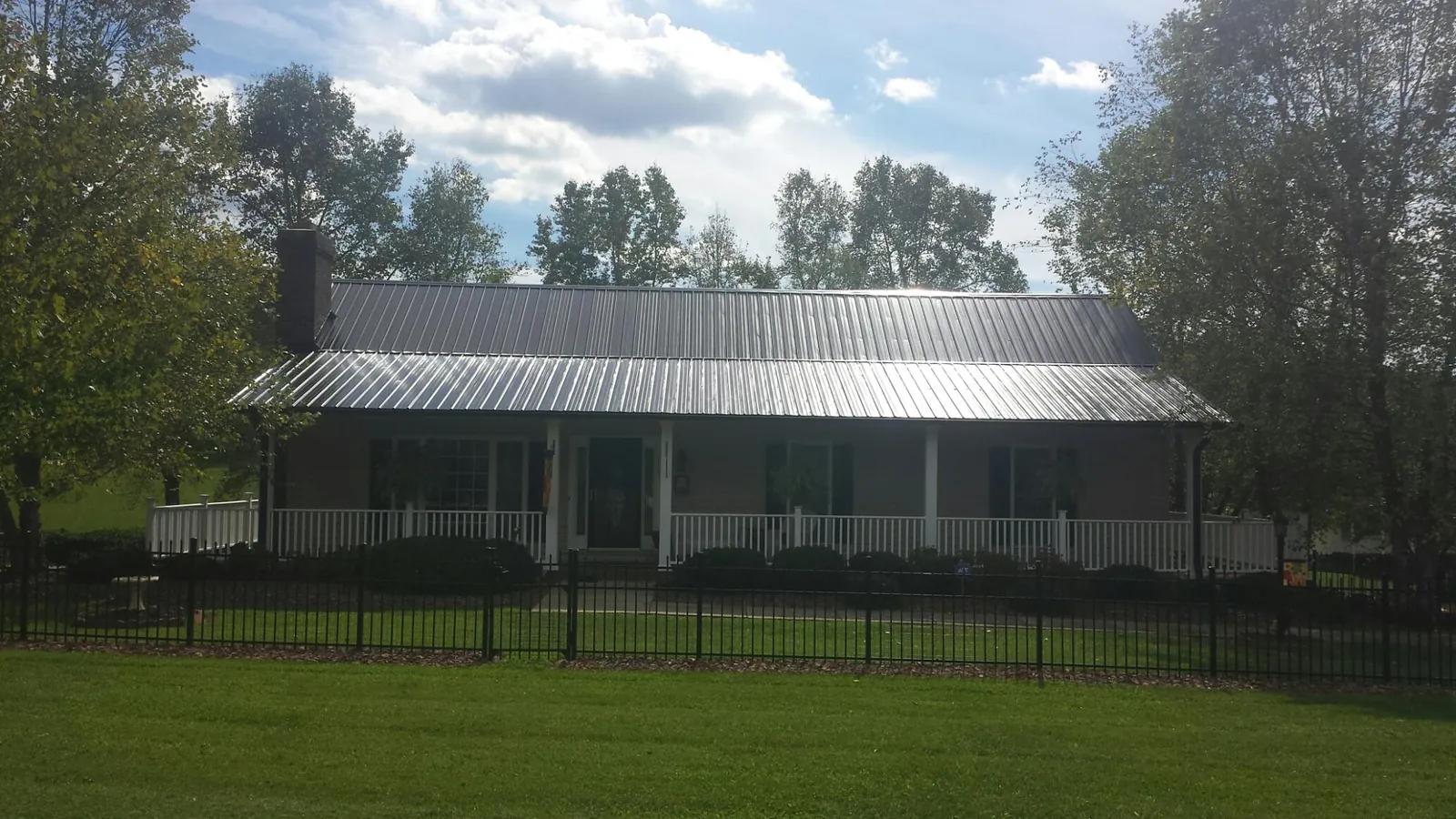 Gray metal roof on a brick ranch with a full width front porch — Gutter Guard Installation work by our crew in Cardington