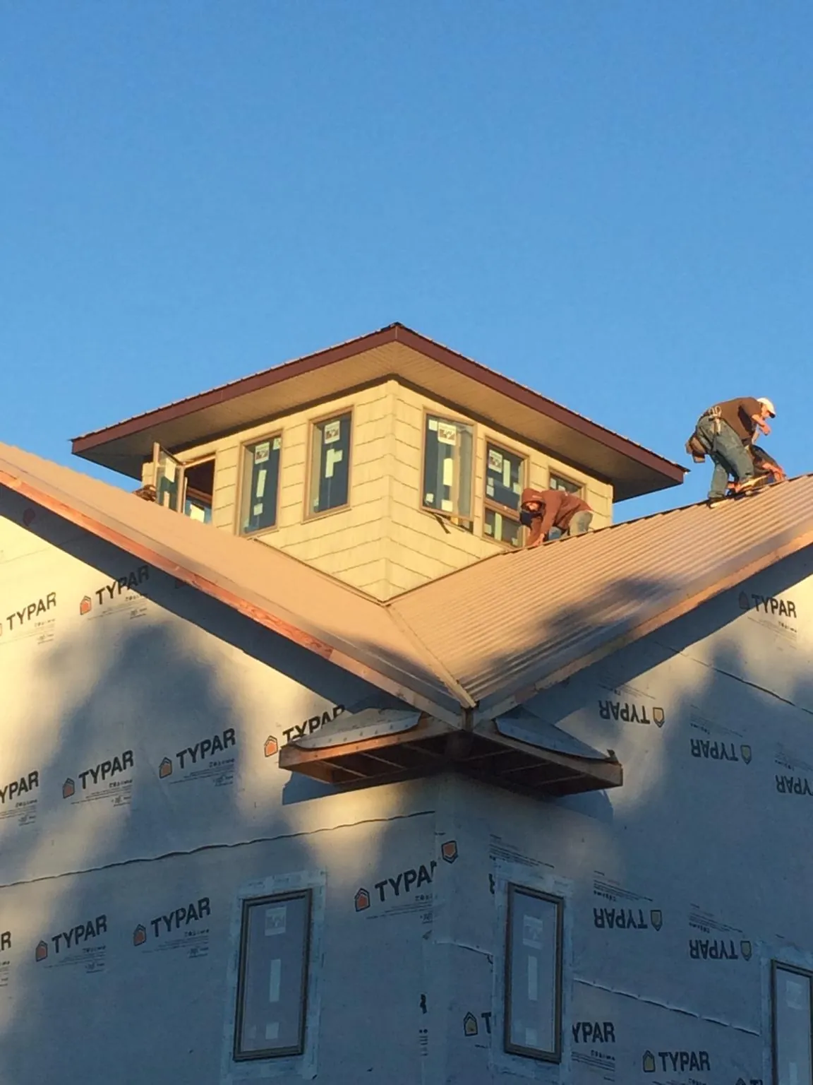 Roofers working around a rooftop cupola on a new metal roof at sunset — Roof Waterproofing in Cardington by Roofing Brothers